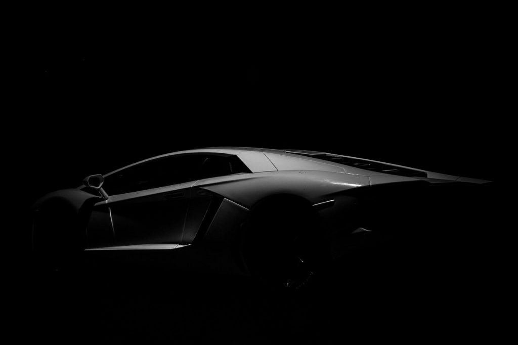 A Lamborghini emerges from the shadows in this dramatic low-light shot, highlighting its sculpted lines and stealthy, high-performance allure.