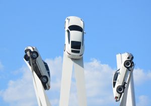 A striking sculpture displays three Porsche cars mounted on tall beams, appearing to soar into the sky as a tribute to the brand’s heritage and innovation.