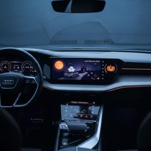 The Audi's interior is illuminated by a Halloween-themed dashboard display featuring a ghost, pumpkins, and a haunted house under an orange moon.
