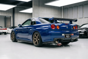 Blue Nissan Skyline GT-R in a clean indoor garage, rear view with large spoiler and circular taillights visible.